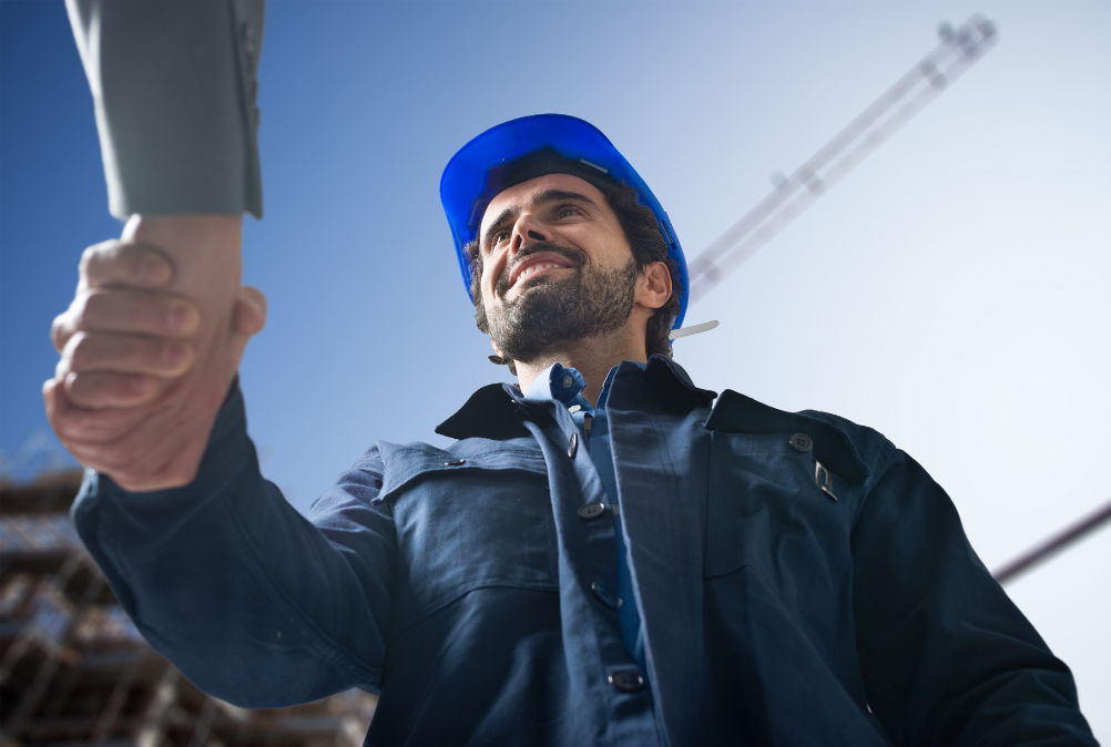 Man wearing hard hat and shaking a persons hand